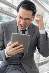 business man is stressed from work ,tablet phone computer in hand - lifestyle business people concept
