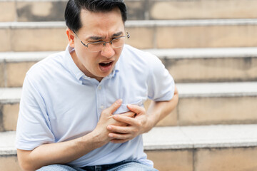 asian businessman suffering from bad pain in his chest heart attack -  business people heart disease concept
