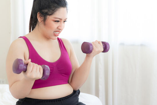 asian fat women , Fat girl , Chubby, overweight plus size attempt exercises with dumbbell lifting in the bedroom - lifestyle Woman diet weight loss overweight problem concept