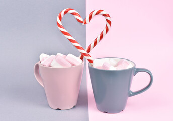 Obraz na płótnie Canvas Happy Valentine day concept. Coffee mugs with marshmallow, heart made of lollipops. Gray and pink background. Festive card for 14 February.