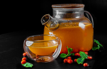 tea pot and Cup of sea buckthorn tea on black background