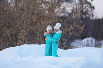 Two girlfriends have fun. Winter walks of girls in the woods, good weather. Joyful meeting and hugs.