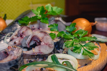 Mackerel, cut into pieces, prepared for salting, with herbs, onions, spices and salt.