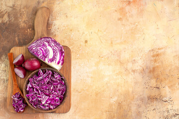 Fototapeta na wymiar top view healthy food concept with some chopped cabbage and red onions on a cutting board for preparation of vegetable salad on a wooden table with copy space