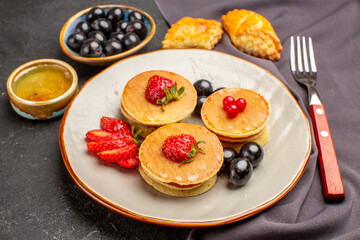 front view yummy pancakes with olives and fruits on dark floor sweet fruit cake