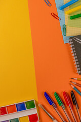 Layout for yellow and orange background. paints, brush, pens, pencils, notebook, paper clips, felt-tip pens