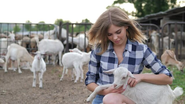 Adorable sexy girl posing with white goat on the farm