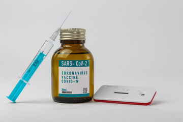 Impfstoffbehälter mit Spritze und Nadel - daneben ein Test auf Antikörper/Immunität