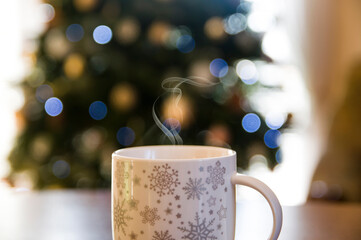 Winter coffee cup with smoke and bokeh Christmas lights background
