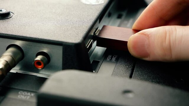 Close-up detail of a modern TV set with ports. The hand inserts a memory card into the usb port of the TV. Interactive internet television. Selective focus, shallow depth of field