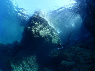 free diver  underwater sun beams and sun rays freediver apnea man exploring underwater rocks 