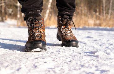 Male feet in brown boots stand in the snow. Winter travel
