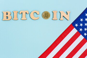 American flag, bitcoin and wooden letters on blue background. New economy on the new virtual money trading.