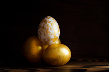 Golden Eggs on dark wooden background. A background for celebrating Easter Top view and copy space Flatlay. Dark background and Minimal black trend 2020. Generous accommodation for copy space.
