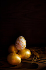 Golden Eggs on dark wooden background. A background for celebrating Easter Top view and copy space Flatlay. Dark background and Minimal black trend 2020. Generous accommodation for copy space.