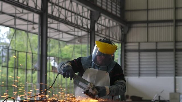 Metalworker wearing face shield and clothing PPE griding metal in factory-- need stabilizer 