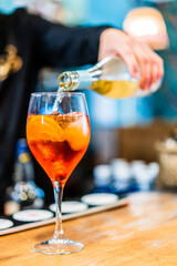 bartender serving orange cocktail with citrus slices decorating the glass
