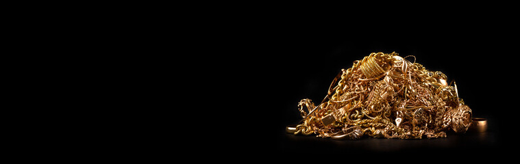 Scrap gold jewelry on black background. Wide horizontal banner with empty copy space for text.