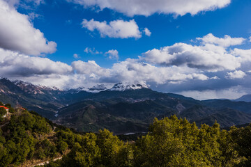 Fototapeta na wymiar Snowy peak Stroggoula , in Tzoumerka mountain range covered by clouds