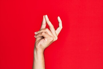 Arm of caucasian white young man over red isolated background snapping fingers for success, easy...