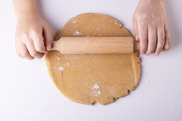 rolling out gingerbread dough with a wooden rolling pin, top view