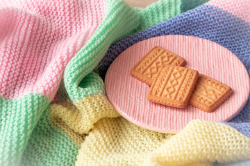 Golden cookies with knitted effect scattered on a knitted blanket. Relaxed or romantic mood concept. Christmas life style