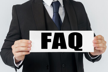 A businessman holds a sign in his hands which says FAQ