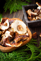 Dehydrated penny bun, boletus edulis mushrooms in a wooden bowl with a green spruce twigs.
