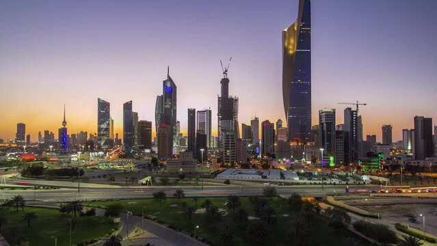 Skyline with Skyscrapers day to night transition timelapse in Kuwait City downtown illuminated at dusk. Aerial view from rooftop. Kuwait City, Middle East.