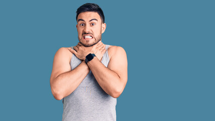 Young handsome man wearing swimwear and sleeveless t-shirt shouting suffocate because painful strangle. health problem. asphyxiate and suicide concept.