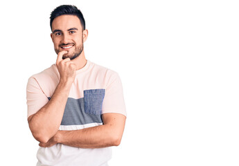 Young handsome man wearing casual clothes looking confident at the camera with smile with crossed arms and hand raised on chin. thinking positive.