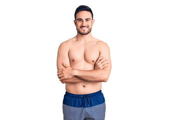 Fototapeta premium Young handsome man wearing swimwear happy face smiling with crossed arms looking at the camera. positive person.