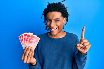 Young african american man holding 20 israel shekels banknotes smiling with an idea or question...