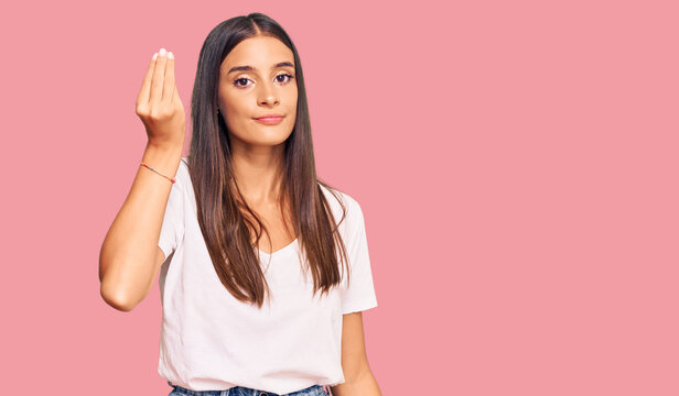 Young hispanic woman wearing casual white tshirt doing italian gesture with hand and fingers confident expression