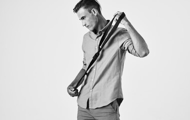 Retro photo of a man in a shirt, tie in hand and light background side view