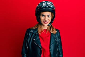 Hispanic young woman wearing motorcycle helmet looking positive and happy standing and smiling with a confident smile showing teeth