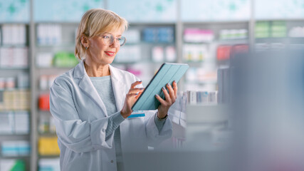 Pharmacy Drugstore: Mature Experienced Female Farmacist Uses Digital Tablet Computer to Arrange,...