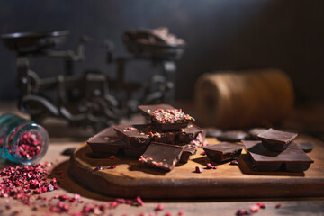 Raw vegan handmade dark Chocolate with dried fruits and berries, wooden rustic table, dark background.  Homemade healthy dessert. Copy space.