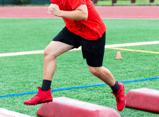 Football athlete running over red barriers at summer camp