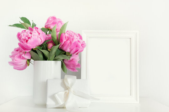 Pink peony in vase with gift photo frame on white. Mothers day.