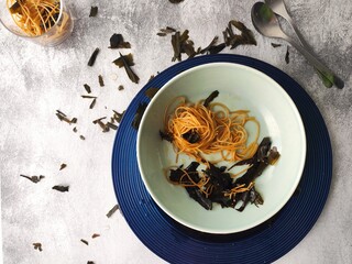 Kombu algae spaghetti fried in extravirgin olive oil and served in a blue sea plate. A delicious vegetarian dish from Mediterranean sea flavours