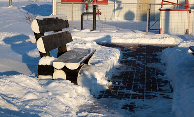 Winter roadside black bench. Snow-covered blask bench © Sofya