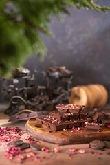 Raw vegan handmade dark Chocolate with dried fruits and berries, wooden rustic table, dark background.  Homemade healthy dessert. Copy space.