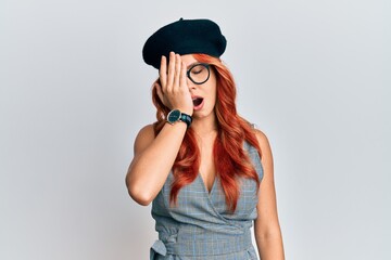 Young redhead woman wearing fashion french look with beret yawning tired covering half face, eye and mouth with hand. face hurts in pain.