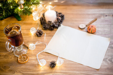 A blank sheet of paper under the christmas tree. A letter to Santa Claus. Christmas decor on a wooden table