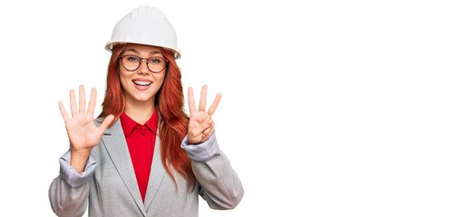 Young redhead woman wearing architect hardhat showing and pointing up with fingers number eight while smiling confident and happy.