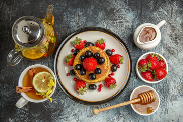 top view yummy pancakes with fruits and tea on light floor sweet fruit breakfast