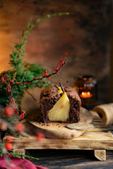 Chocolate pear sponge cake with whole fruits, wooden rustic table. Pear pie with christmas tree brush, candle. Winter homemade dessert. Copy space, selective focus.