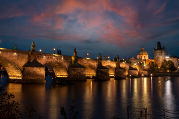 charles bridge and st. vita church lights from street lights are reflected on the surface of the vltava river in the center of prague at night in the czech republic