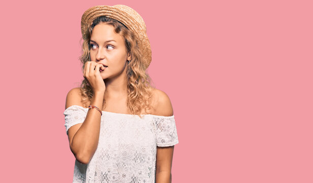 Beautiful caucasian woman wearing summer hat looking stressed and nervous with hands on mouth biting nails. anxiety problem.